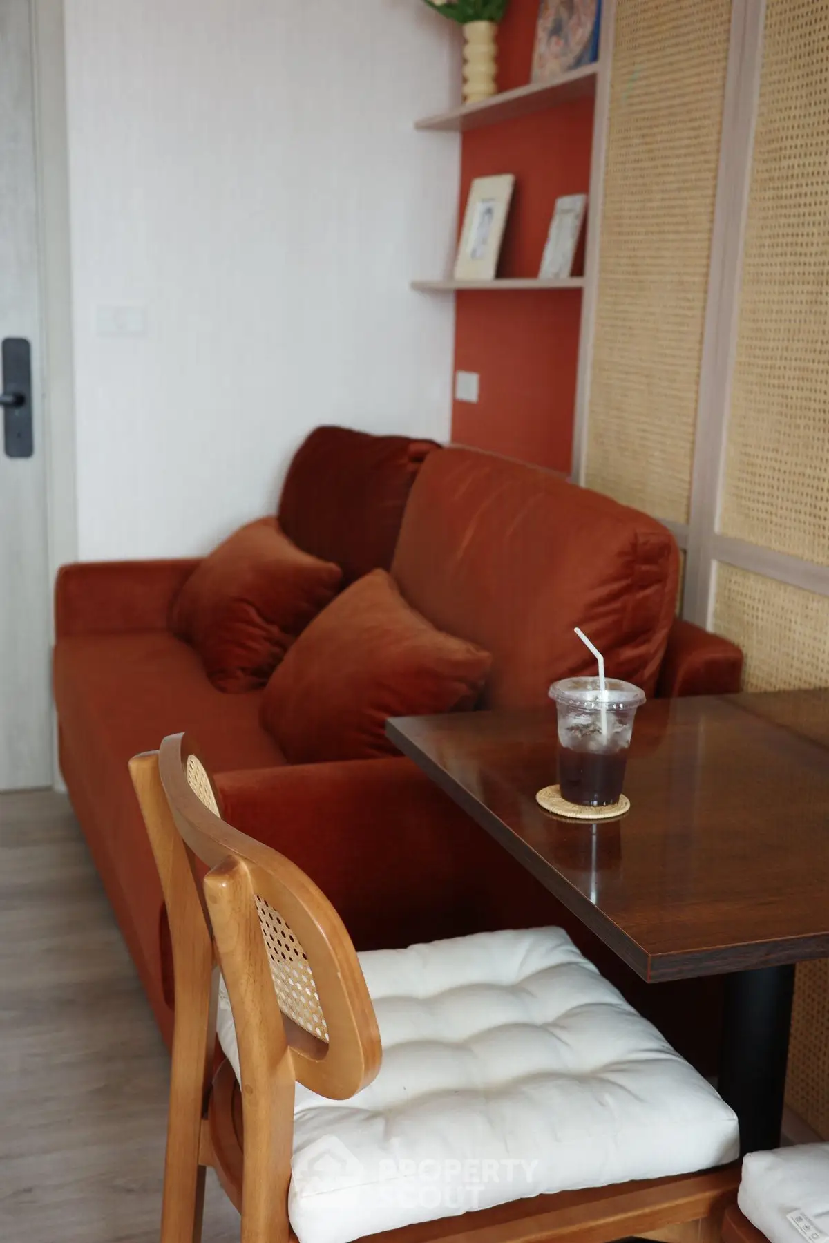 Cozy living room with plush orange sofa and stylish wooden chair, perfect for relaxation.