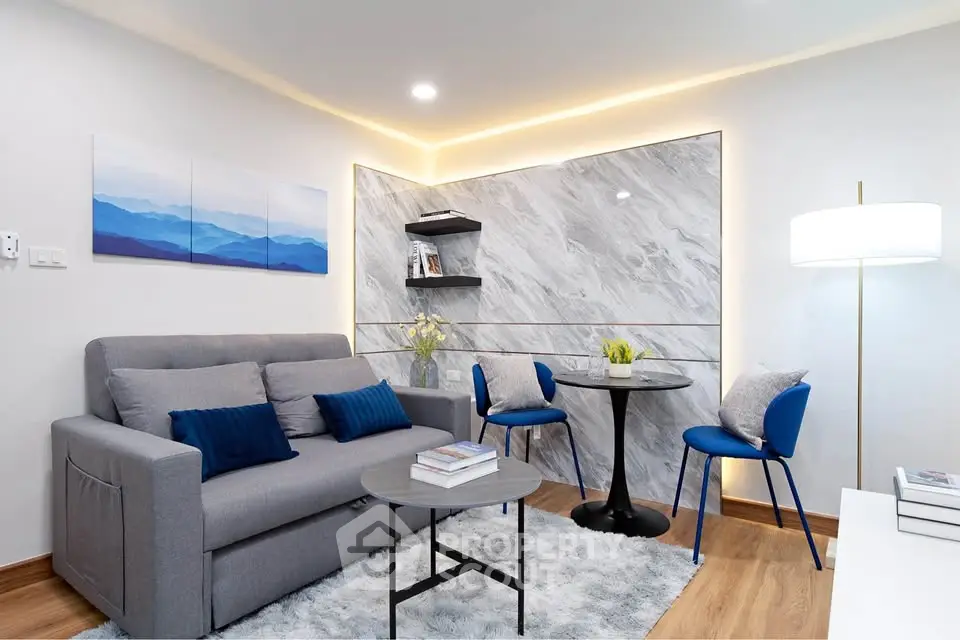 Modern living room with stylish decor, featuring a cozy gray sofa, elegant lighting, and contemporary wall art.