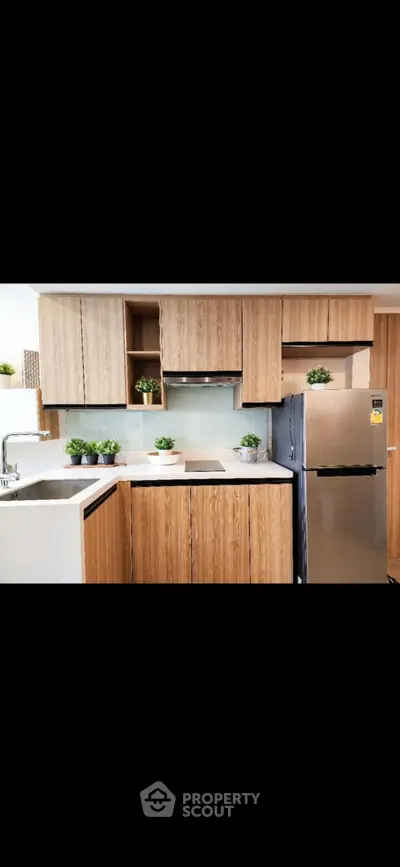 Modern kitchen with sleek wooden cabinets and stainless steel appliances in a stylish apartment.