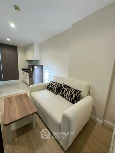 Modern living room with cozy sofa and stylish kitchen in open layout apartment.