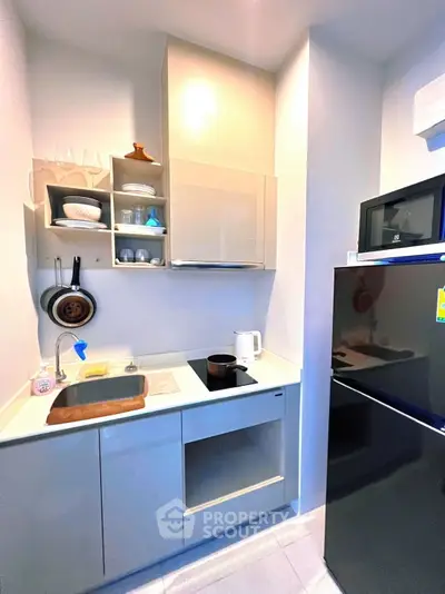 Compact modern kitchen with sleek cabinets and appliances in a cozy apartment.