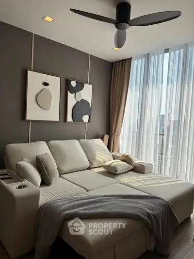 Modern living room with cozy sofa and abstract art, featuring large windows with city view.