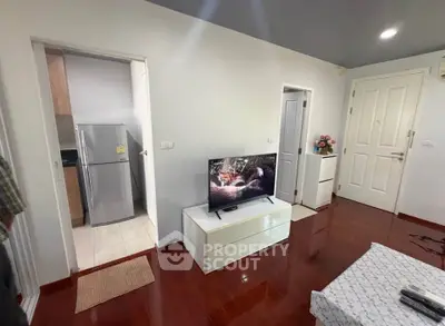 Charming living room with sleek TV stand and modern kitchen view, perfect for cozy living.