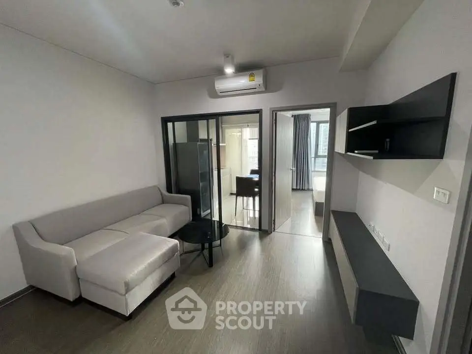 Modern living room with sleek furniture and open layout, featuring a cozy sofa and stylish shelving.