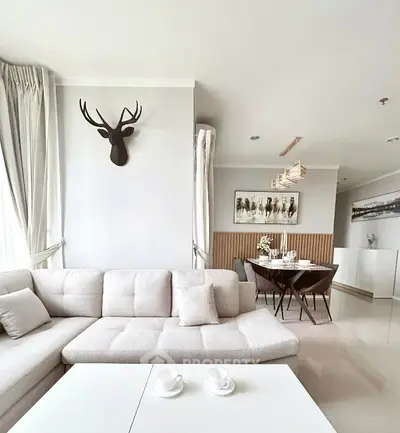 Elegant living room with modern decor and dining area, featuring a stylish deer head wall art.