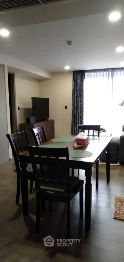 Spacious living room with dining area and modern decor in a well-lit apartment.