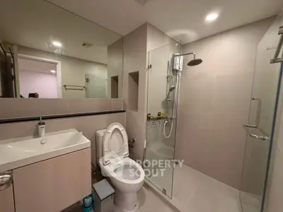Modern bathroom with glass shower and sleek fixtures in contemporary apartment.
