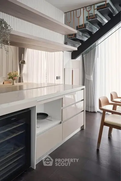 Modern kitchen with sleek design, featuring open layout and stylish dining area under a staircase.