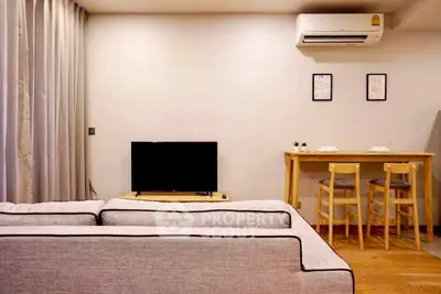 Modern living room with cozy sofa, TV, and dining area featuring wooden furniture and air conditioning.