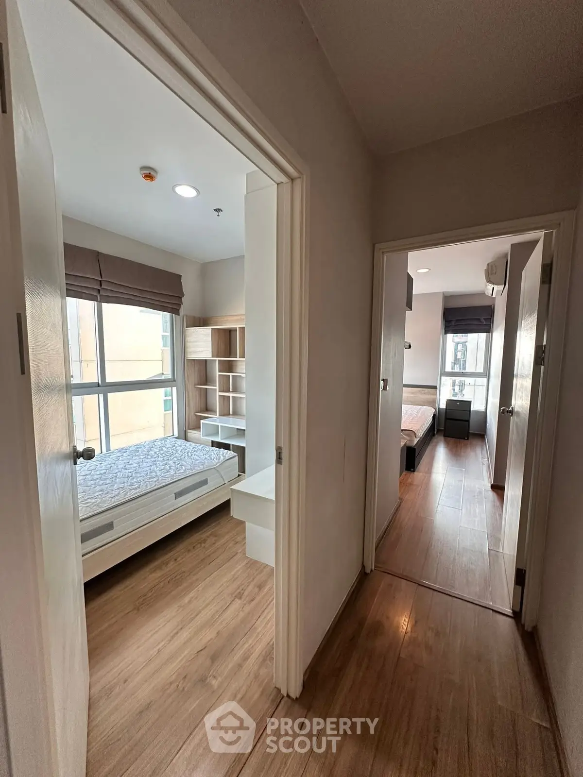 Modern apartment hallway with two cozy bedrooms featuring wooden flooring and ample natural light.