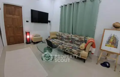 Cozy living room with modern decor, featuring a stylish sofa, glass coffee table, and wall-mounted TV.