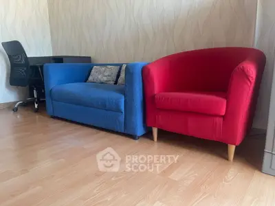 Modern living room with vibrant blue sofa and red armchair, perfect for stylish comfort.