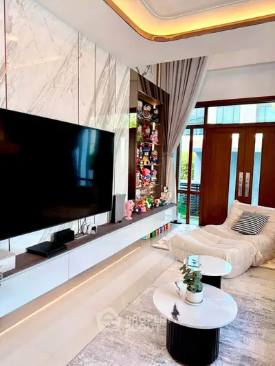 Luxurious modern living room with marble accents and large TV, featuring stylish decor and plush seating.