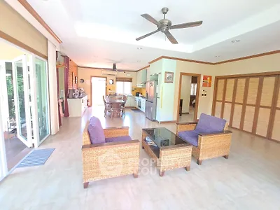 Spacious open-plan living room with stylish wicker furniture and ceiling fan, perfect for modern living.