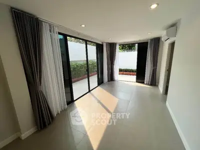 Spacious living room with large windows and garden view, perfect for natural light lovers.