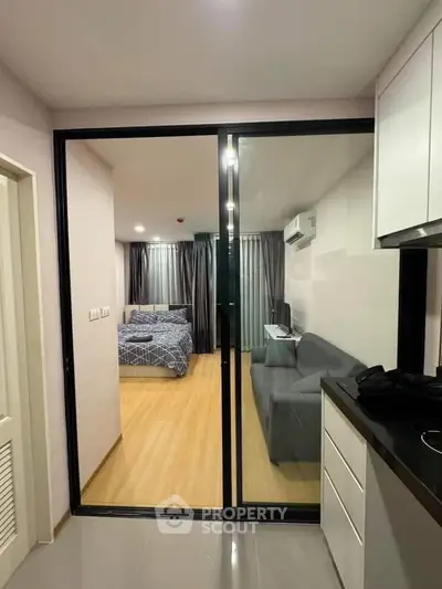 Modern apartment interior with sliding glass doors separating bedroom and living area, featuring sleek design.