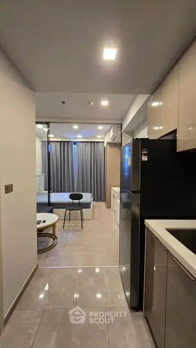 Modern open-layout kitchen leading to a stylish living room with sleek furniture.