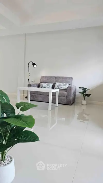 Modern living room with sleek sofa, stylish coffee table, and lush indoor plants on glossy tiled floor.