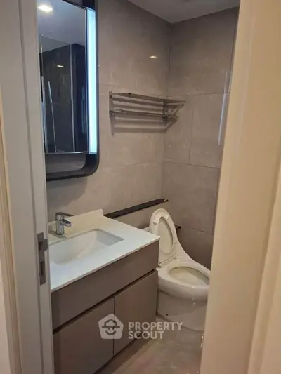 Modern bathroom with sleek vanity and toilet in a compact space.