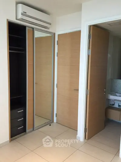 Modern bedroom with mirrored closet doors and sleek wooden finishes.