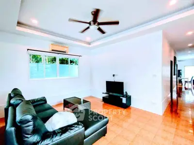 Spacious living room with modern decor and ceiling fan, perfect for relaxation and entertainment.