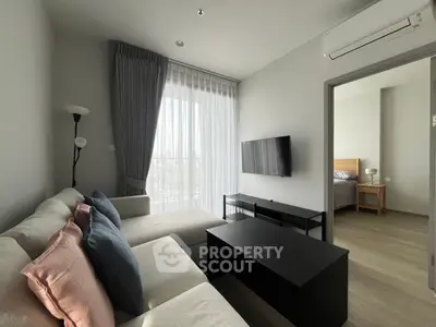 Modern living room with cozy sofa and wall-mounted TV, adjacent to a stylish bedroom.