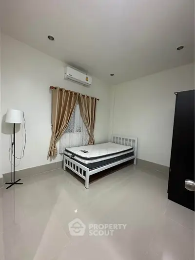 Minimalist bedroom with single bed, air conditioning, and elegant curtains.