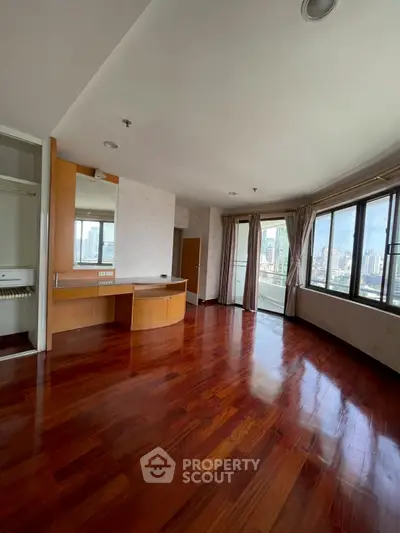 Spacious bedroom with hardwood floors and city view in luxury apartment