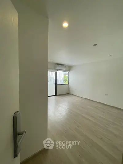 Spacious unfurnished living room with large windows and wooden flooring, perfect for customization.