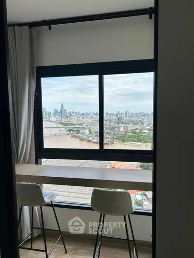 Stunning high-rise apartment with panoramic city and river views from a cozy window seating area.