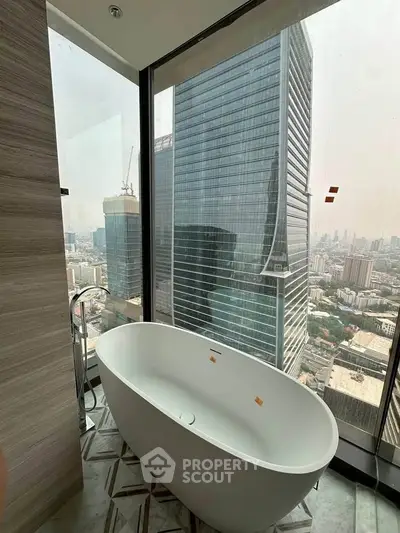 Luxurious bathroom with freestanding bathtub and stunning city view from high-rise window.