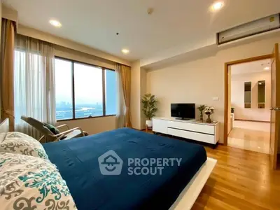 Spacious bedroom with large window offering stunning city views, modern decor, and elegant furnishings.