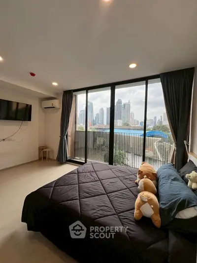 Spacious bedroom with city view and large windows in modern apartment.