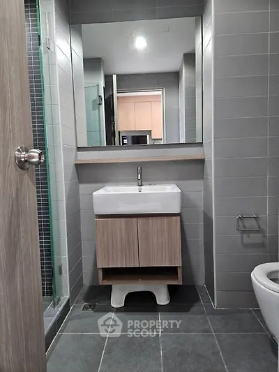 Modern bathroom with sleek sink and large mirror in stylish apartment.