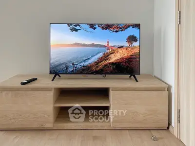Modern living room with sleek TV setup on wooden cabinet, minimalist design.