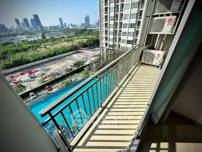 Spacious balcony with stunning city view and poolside ambiance in modern high-rise apartment.