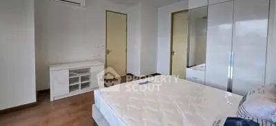 Modern bedroom with sleek white furniture and hardwood floors in a stylish apartment.