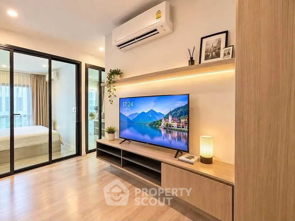 Modern living room with sleek wooden furniture and large TV, adjacent to a cozy bedroom.