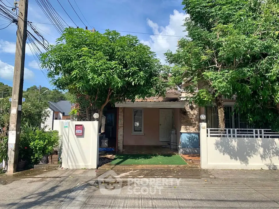 Charming single-story house with lush greenery and gated entrance in a serene neighborhood.