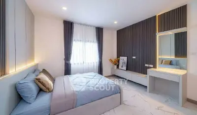 Modern bedroom with elegant decor and natural light, featuring a stylish vanity and cozy bedding.