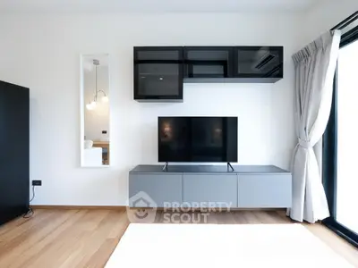 Modern living room with sleek TV unit and large window for natural light.