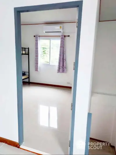 Bright bedroom with bunk bed and air conditioning, featuring a window view and tiled flooring.