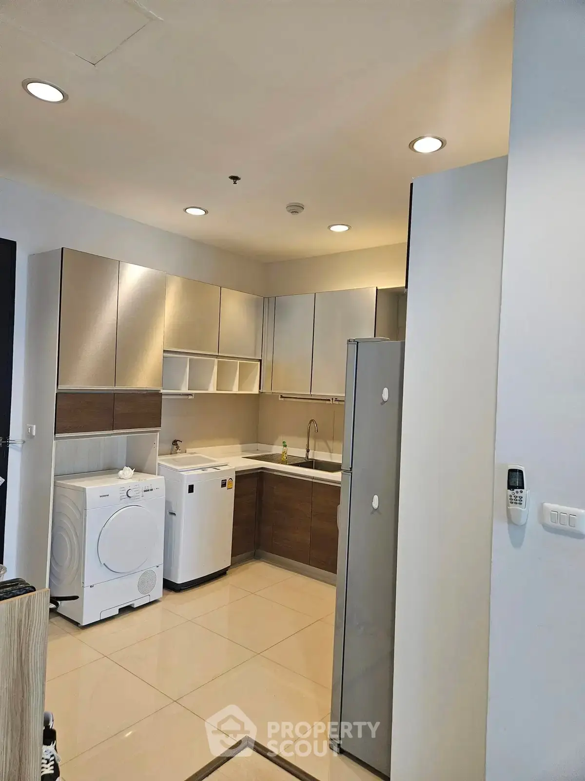 Modern kitchen with sleek cabinets, washing machine, and dishwasher in a stylish apartment.