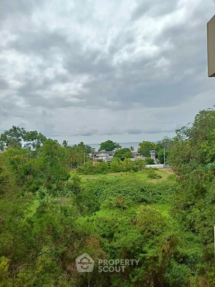 Scenic view of lush greenery and distant buildings under a cloudy sky, perfect for nature lovers.