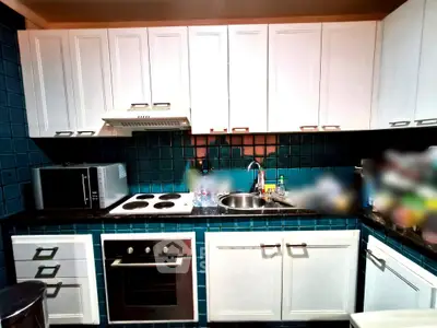 Modern kitchen with white cabinets, blue tiles, and built-in appliances