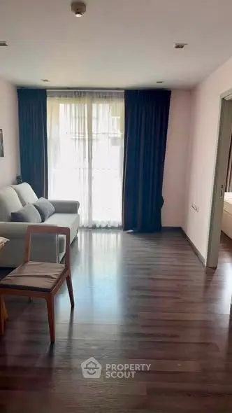 Spacious living room with elegant dark curtains and wooden flooring, perfect for modern living.