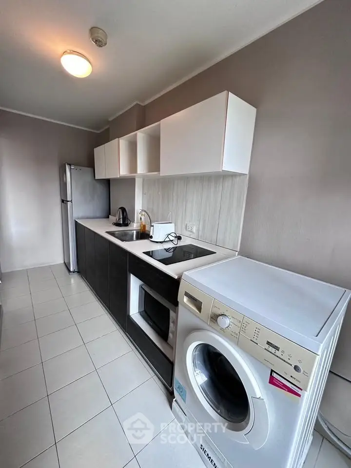 Modern kitchen with sleek appliances and washing machine in a stylish apartment.