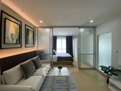 Modern living room with elegant decor and sliding glass doors leading to a cozy bedroom.