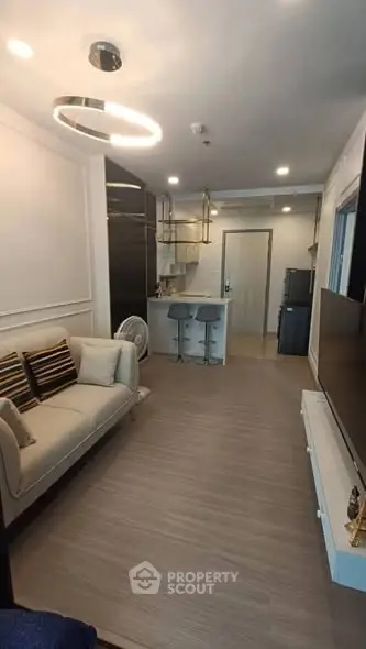 Modern living room with sleek design and open kitchen layout, featuring stylish furniture and contemporary lighting.