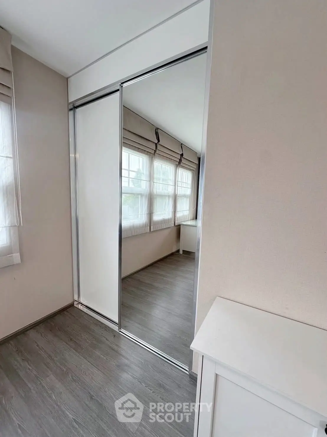 Bright bedroom with mirrored closet doors and large windows